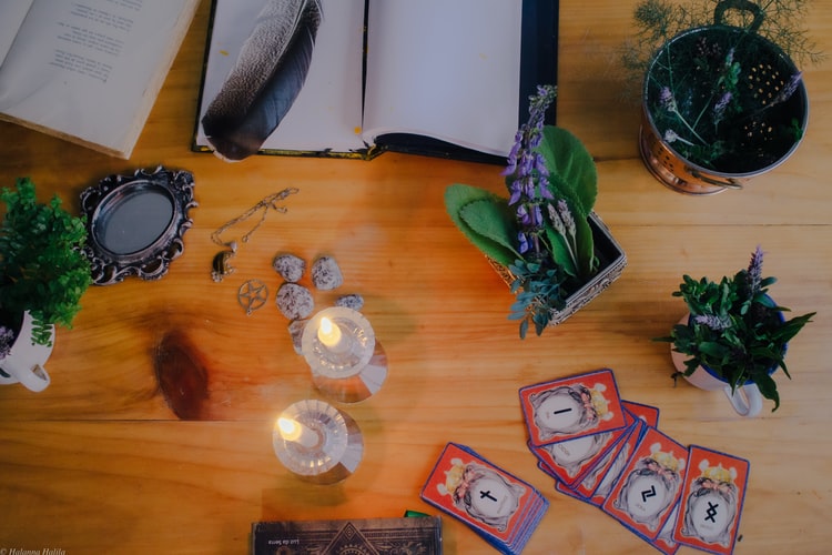 tarot cards, necklace herbs and flowers on a table for type of witch feature image